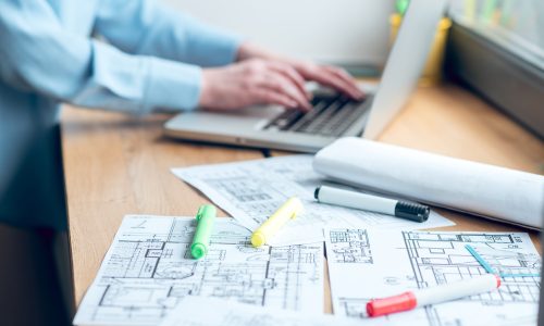 Construction plan on windowsill and female hands near laptop Windows Company Regina, Glass Windows Regina